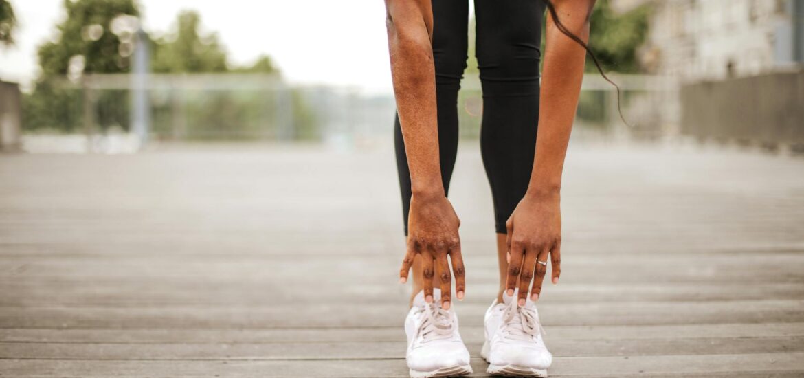 slim woman warming up while training alone on street sports ground
